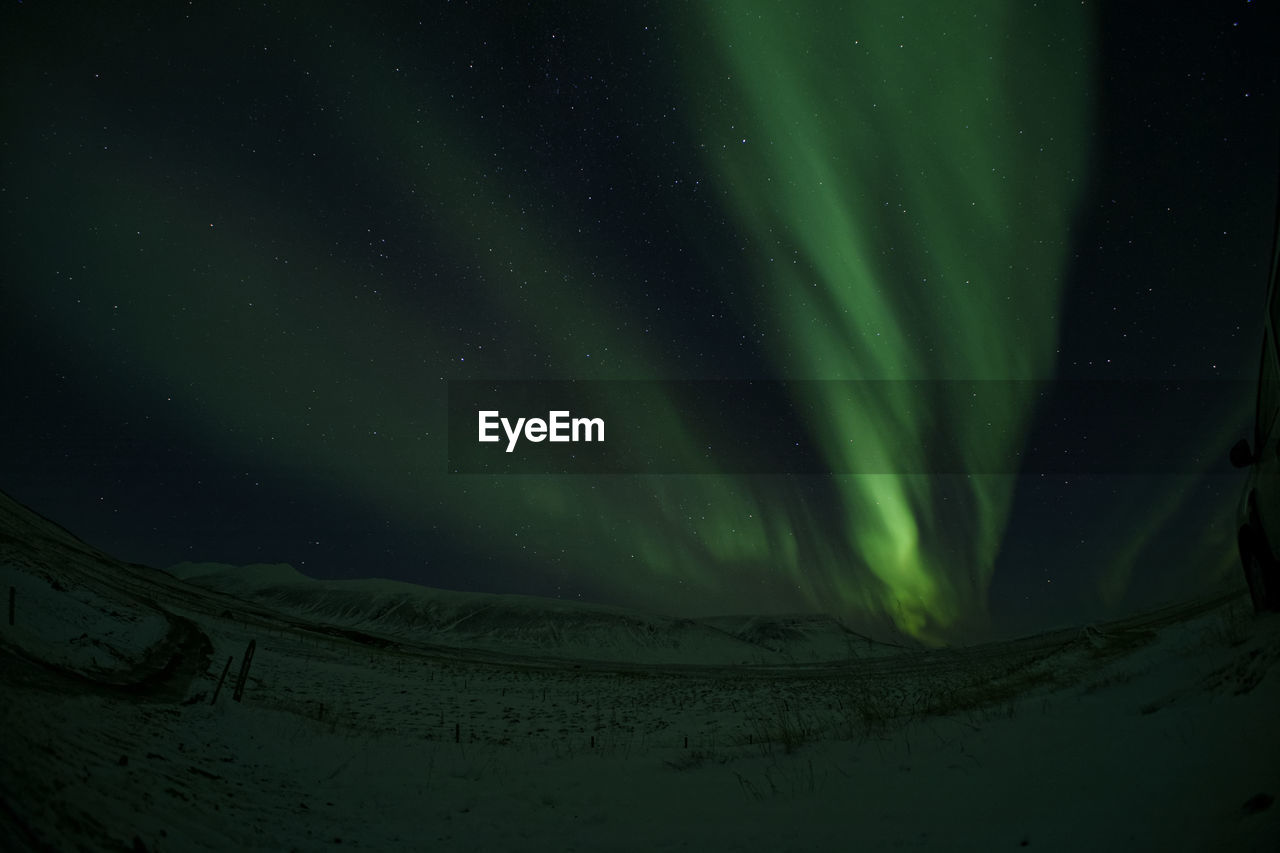 Scenic view of snowcapped landscape against sky with northern lights shinig