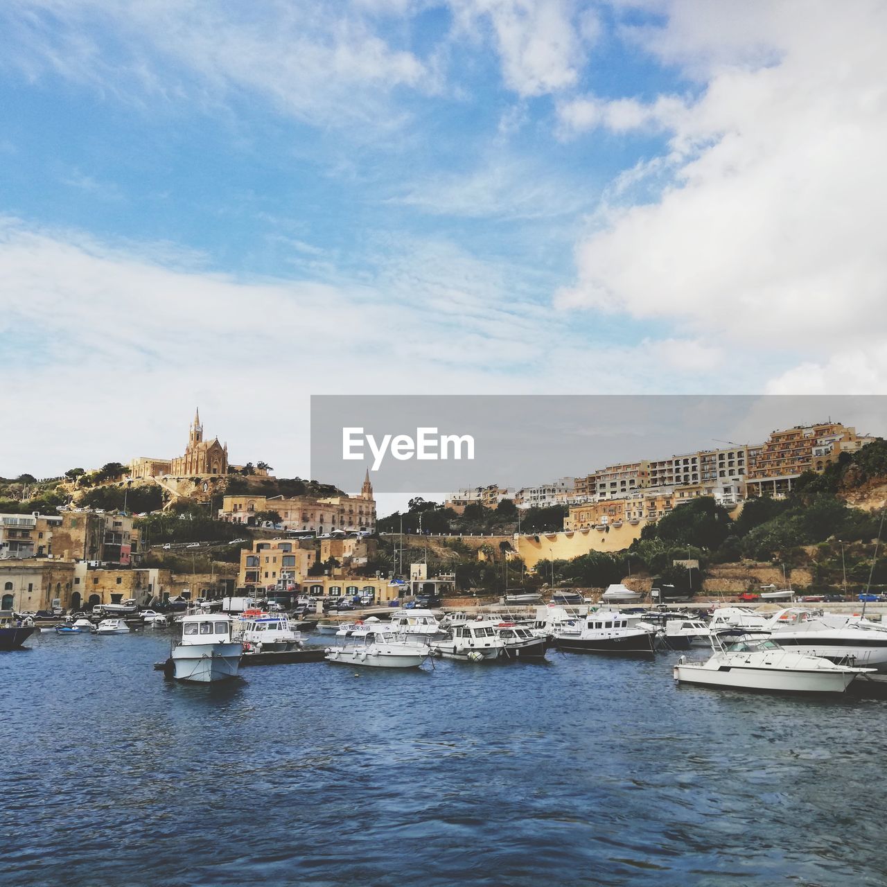 Sailboats moored in harbor against buildings in city