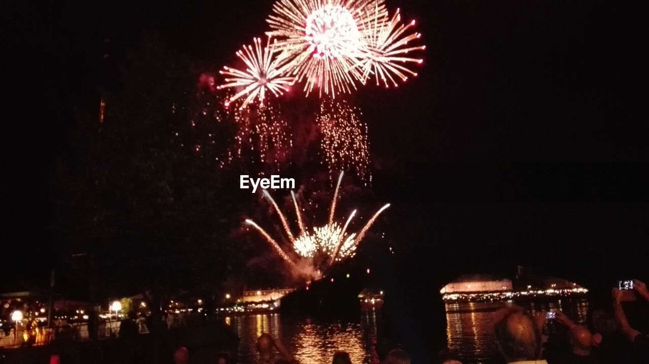 LOW ANGLE VIEW OF FIREWORK DISPLAY OVER RIVER