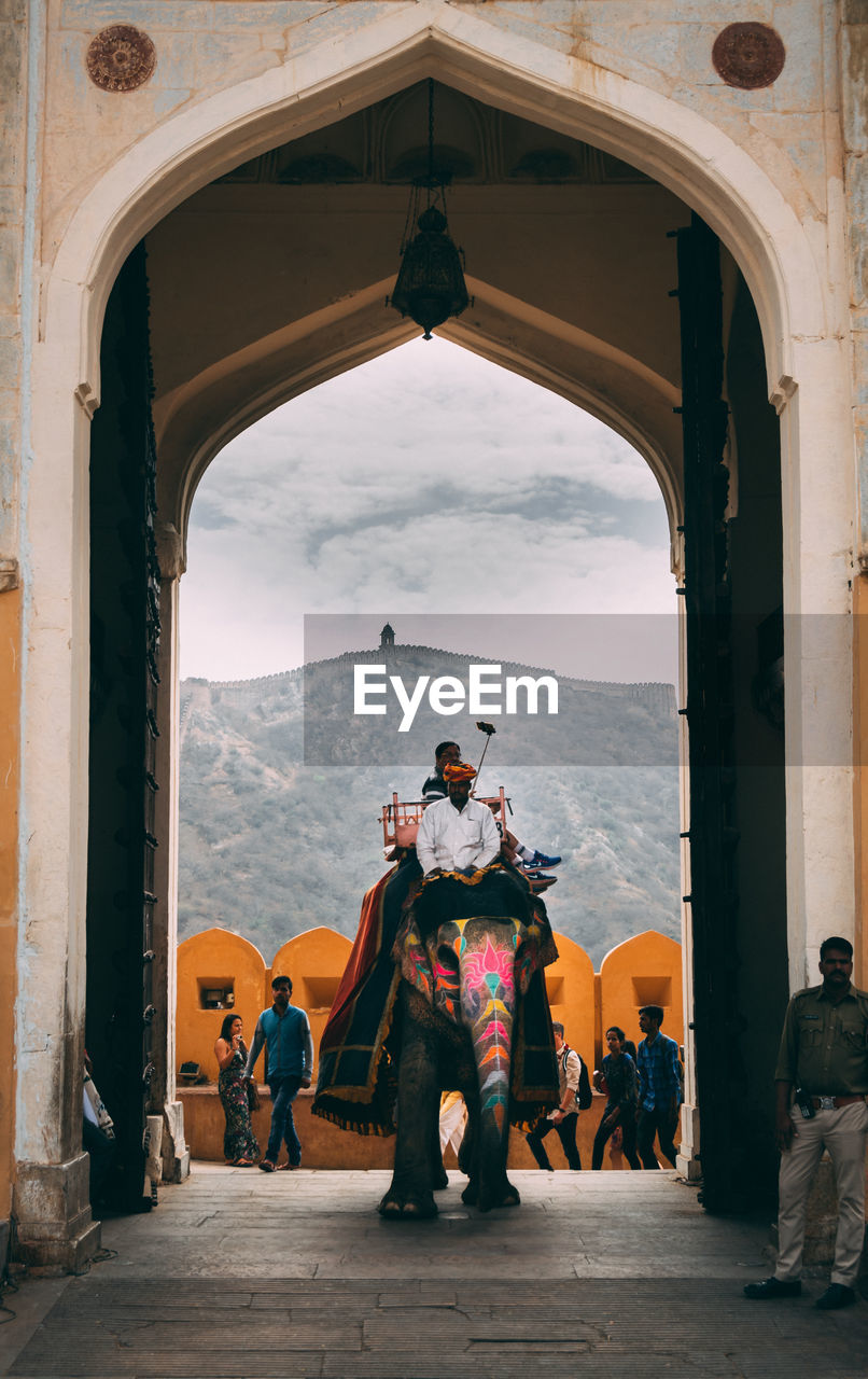 PEOPLE ON HISTORIC BUILDING SEEN THROUGH ARCH