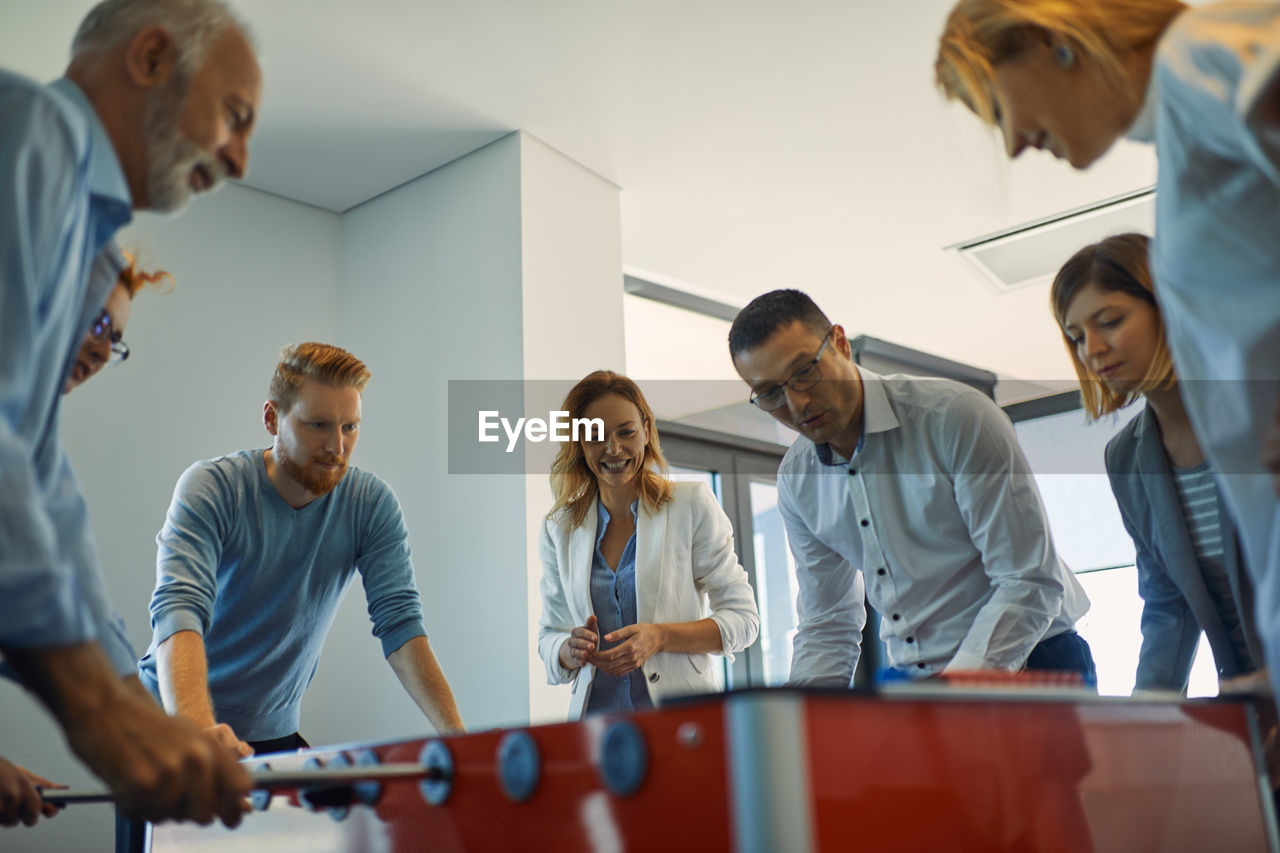 Colleagues playing foosball in office