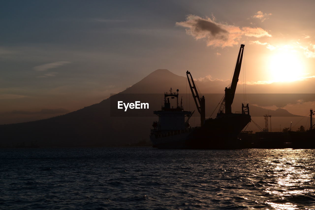 Silhouette ship in sea against sky during sunset