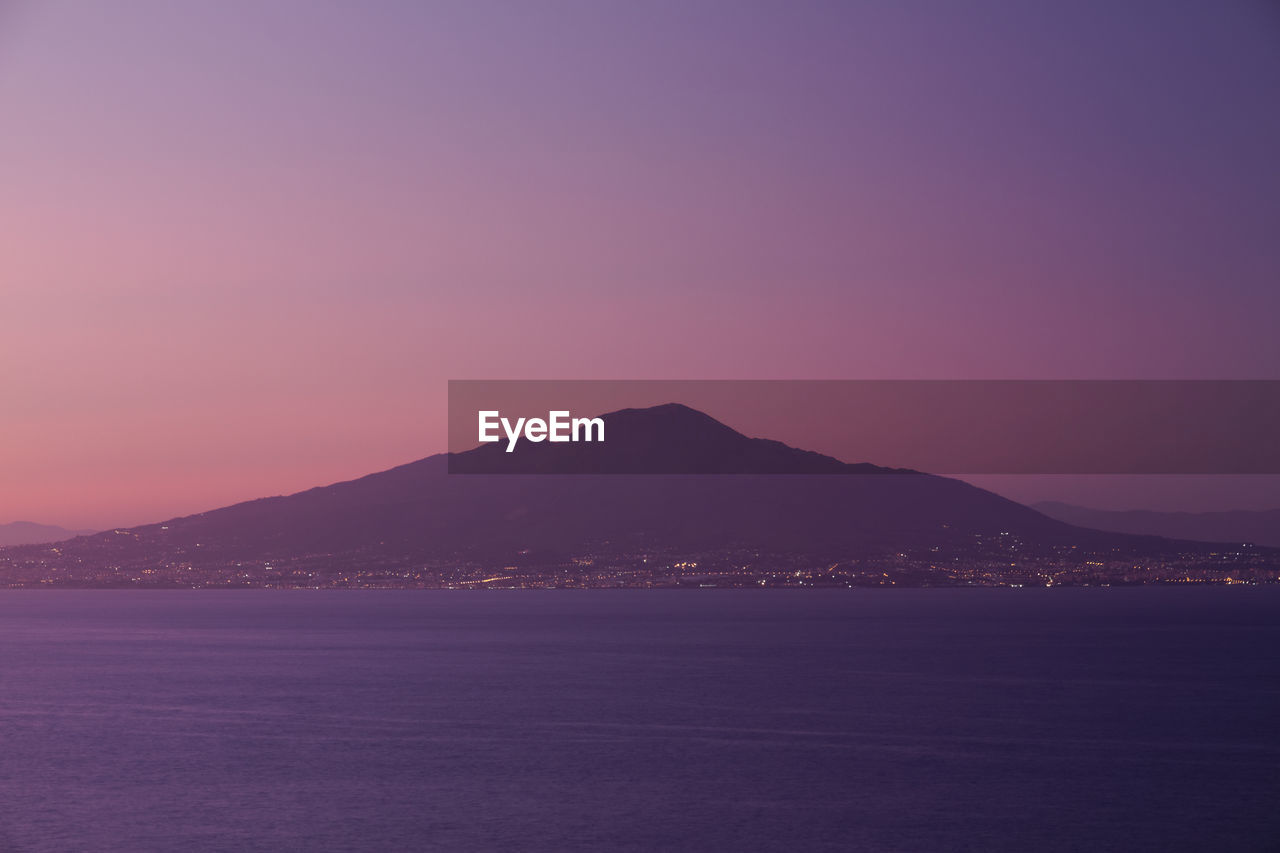 Scenic view of sea and mountain against clear sky during sunset