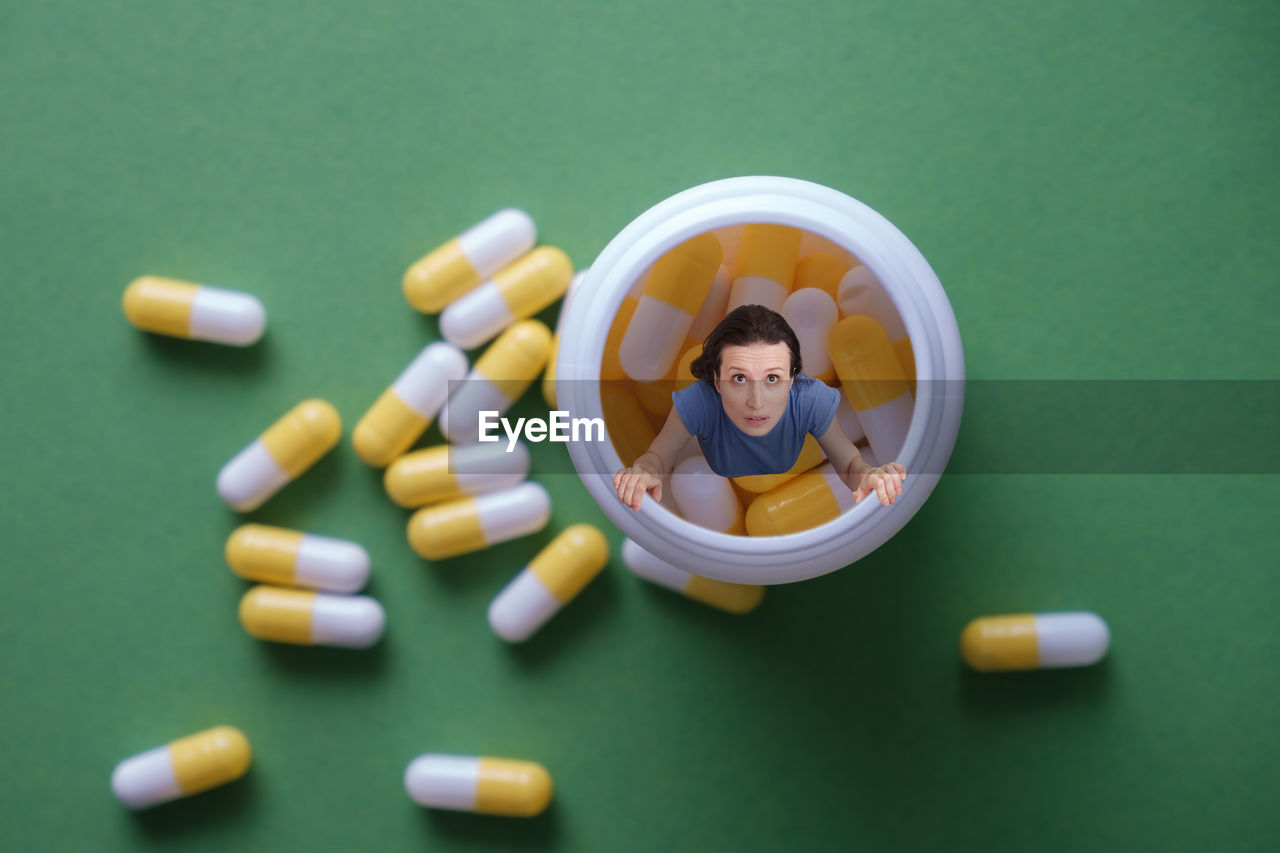 pill, dose, healthcare and medicine, medicine, colored background, pharmaceutical drug, indoors, capsule, large group of objects, drug, studio shot, hand, high angle view, adult, one person, directly above, green background, nutritional supplement, men