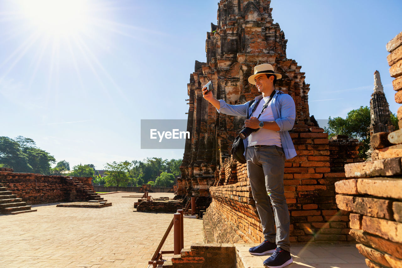 Full length of man taking selfie while standing at old building