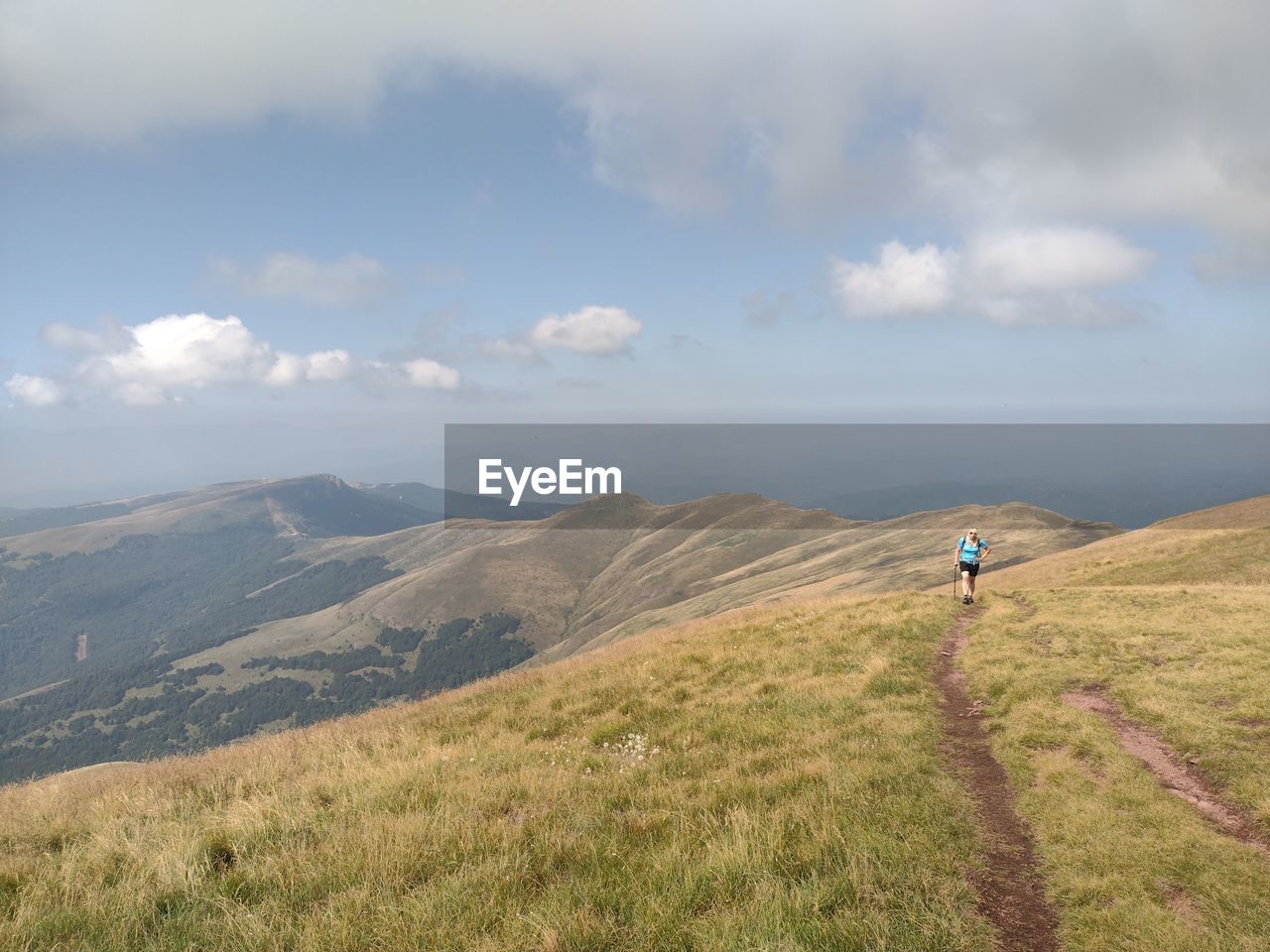 Rear view of man standing on mountain against sky