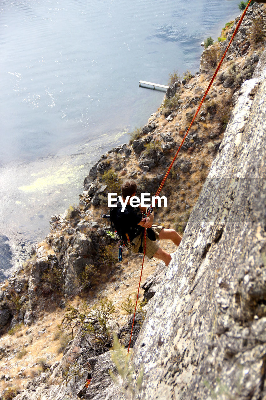 High angle view of man rock climbing against sea