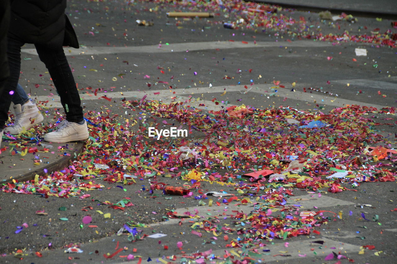 Low section of people walking by confetti on street