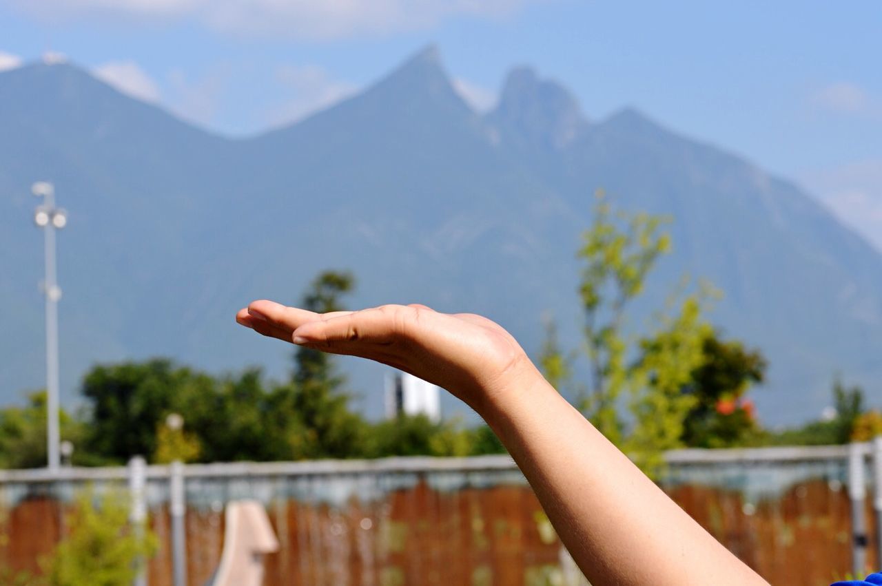 Cropped image of hand against mountain