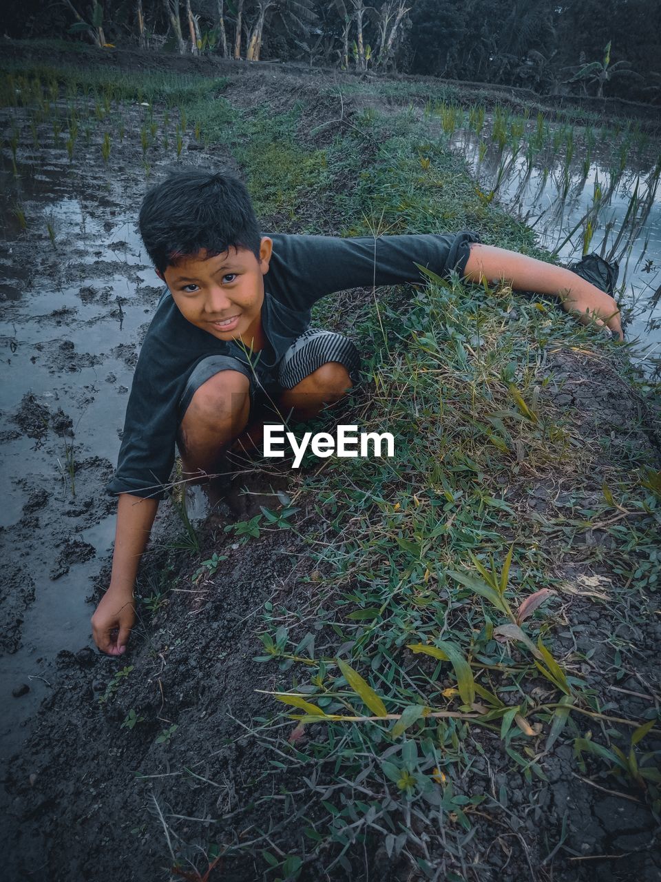 High angle portrait of boy crouching on grassy land