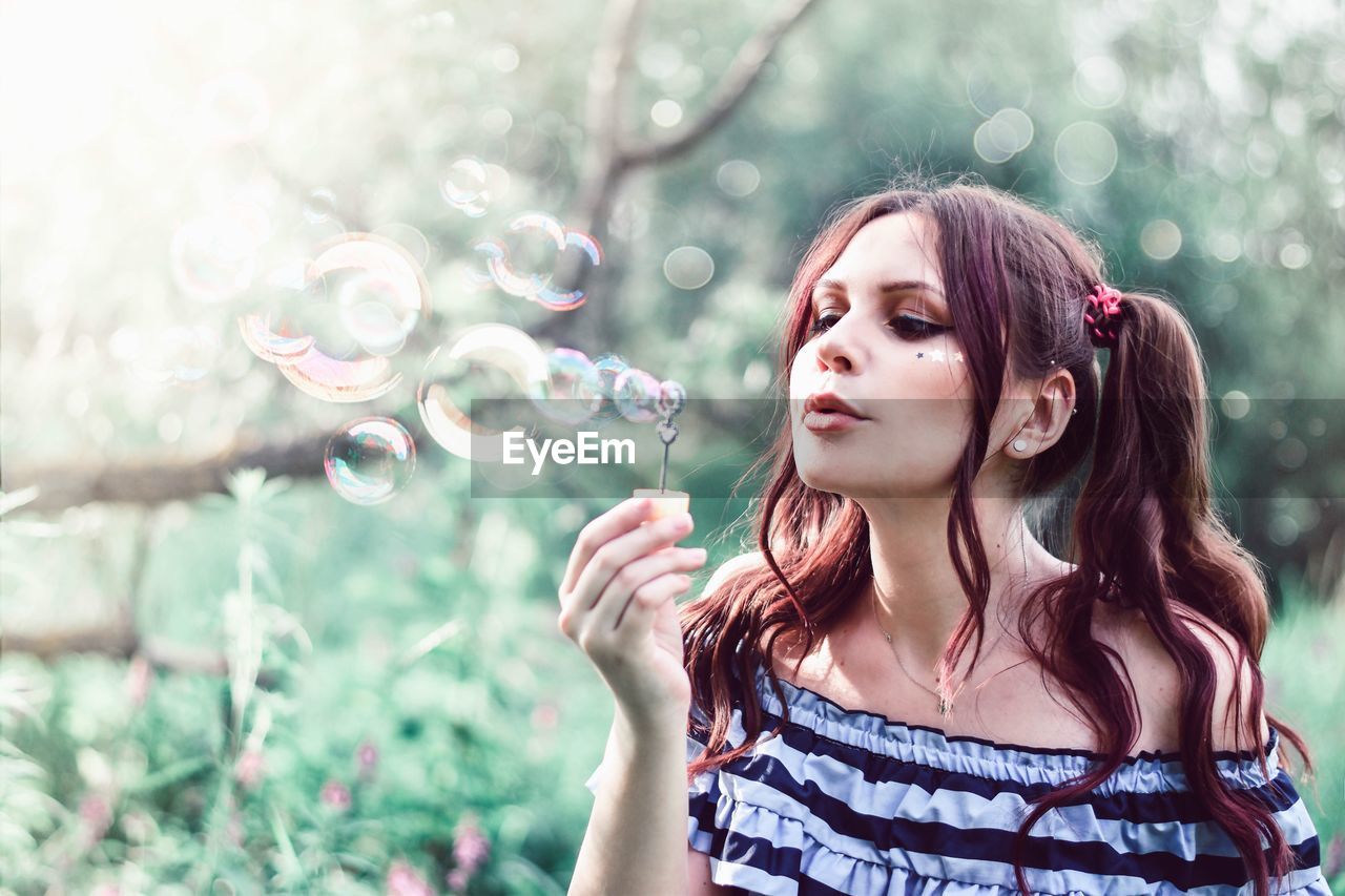 BEAUTIFUL YOUNG WOMAN WITH BUBBLES IN PARK