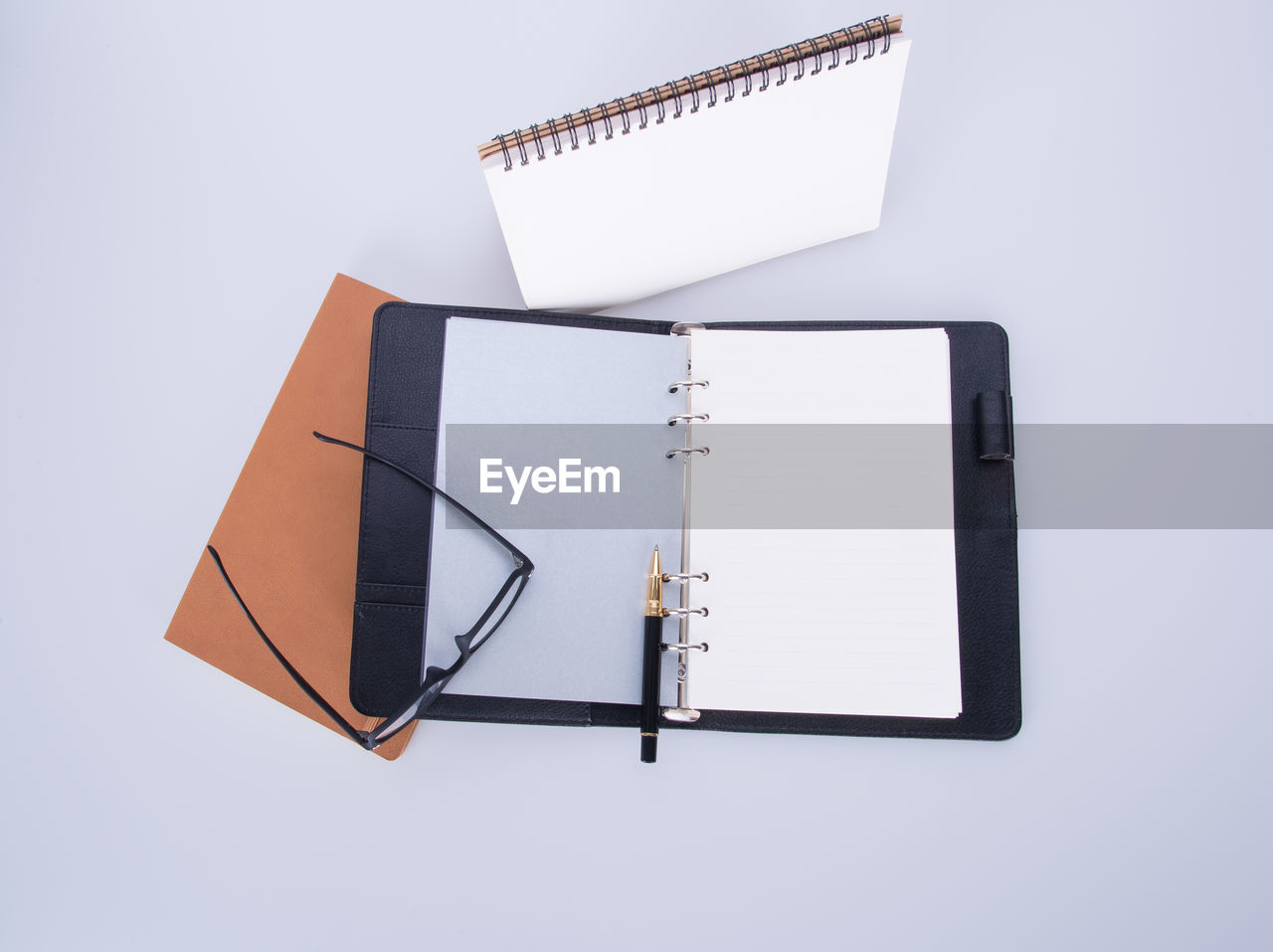 High angle view of books with eyeglasses and pen on white background