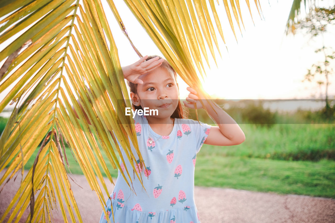 Portrait of a cute girl standing against trees