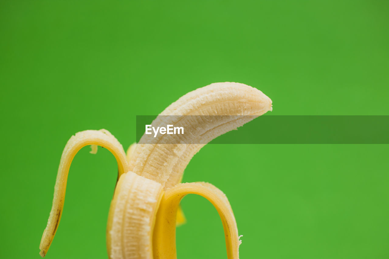 Close-up of a peeled banana against green background