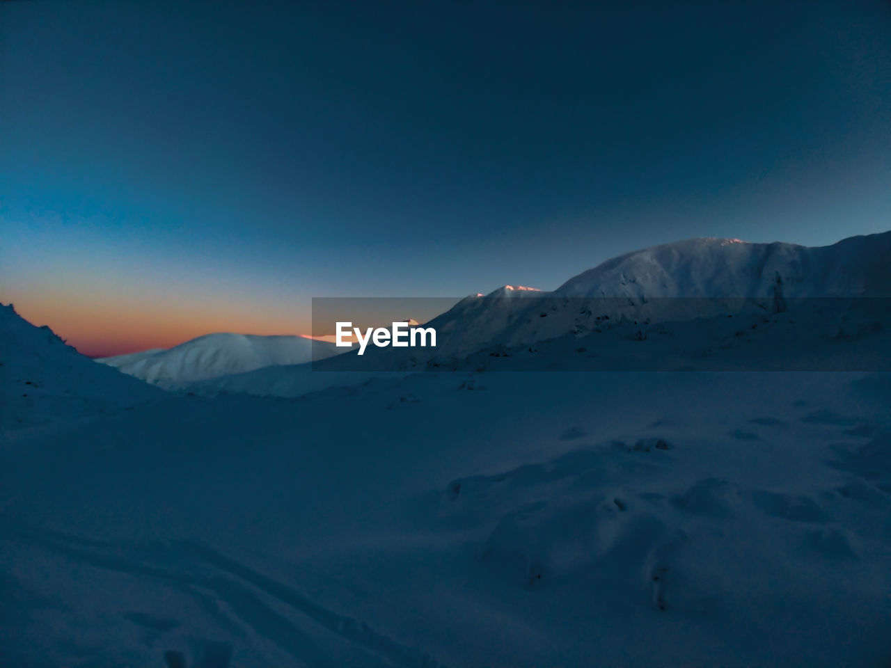 Scenic view of snowcapped mountains against sky during last faze of sunset