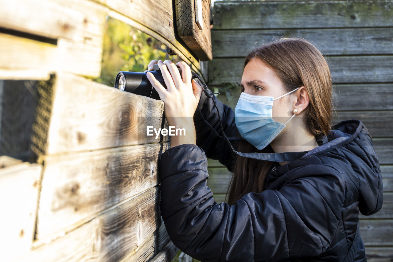 PORTRAIT OF YOUNG WOMAN PHOTOGRAPHING THROUGH CAMERA