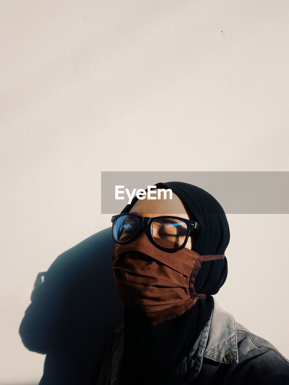 Close-up of woman wearing flu mask standing by wall