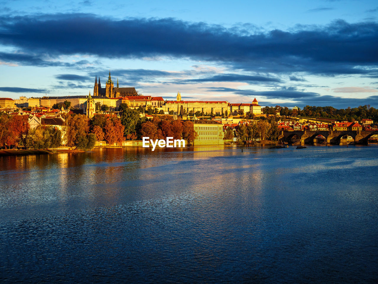 RIVER BY BUILDINGS AGAINST SKY DURING SUNSET