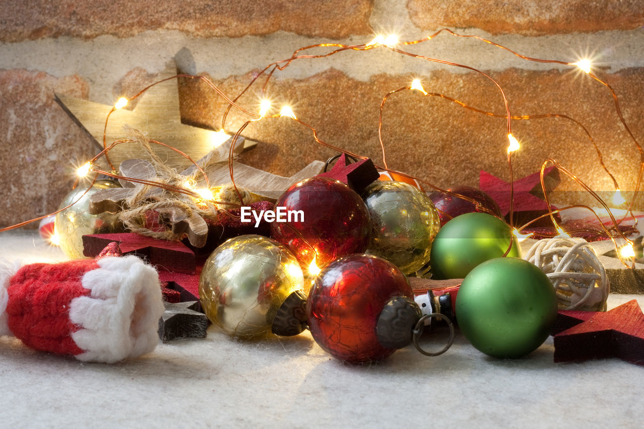 Close-up of christmas decoration christmas ornaments and christmas lights in front of a brick wall