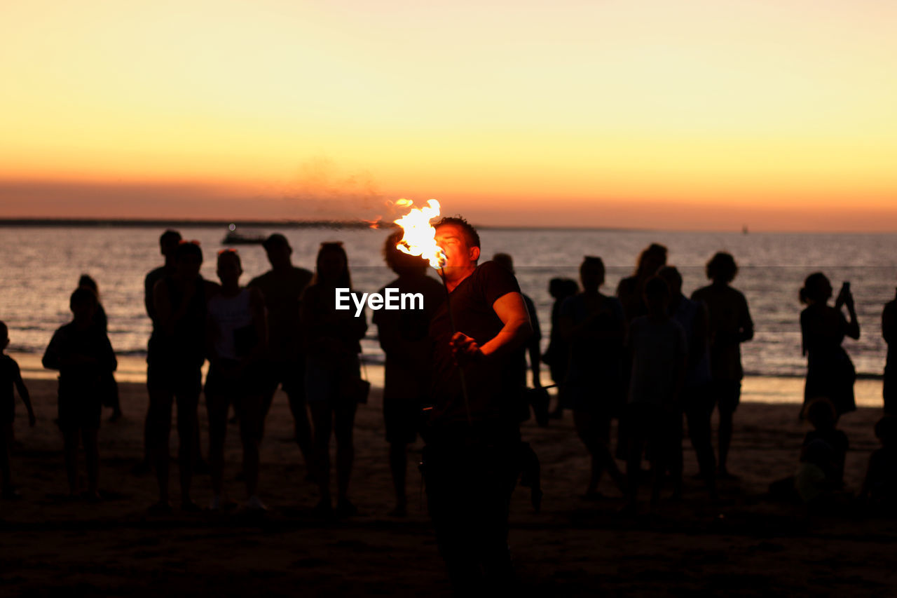 Group of people on beach during sunset