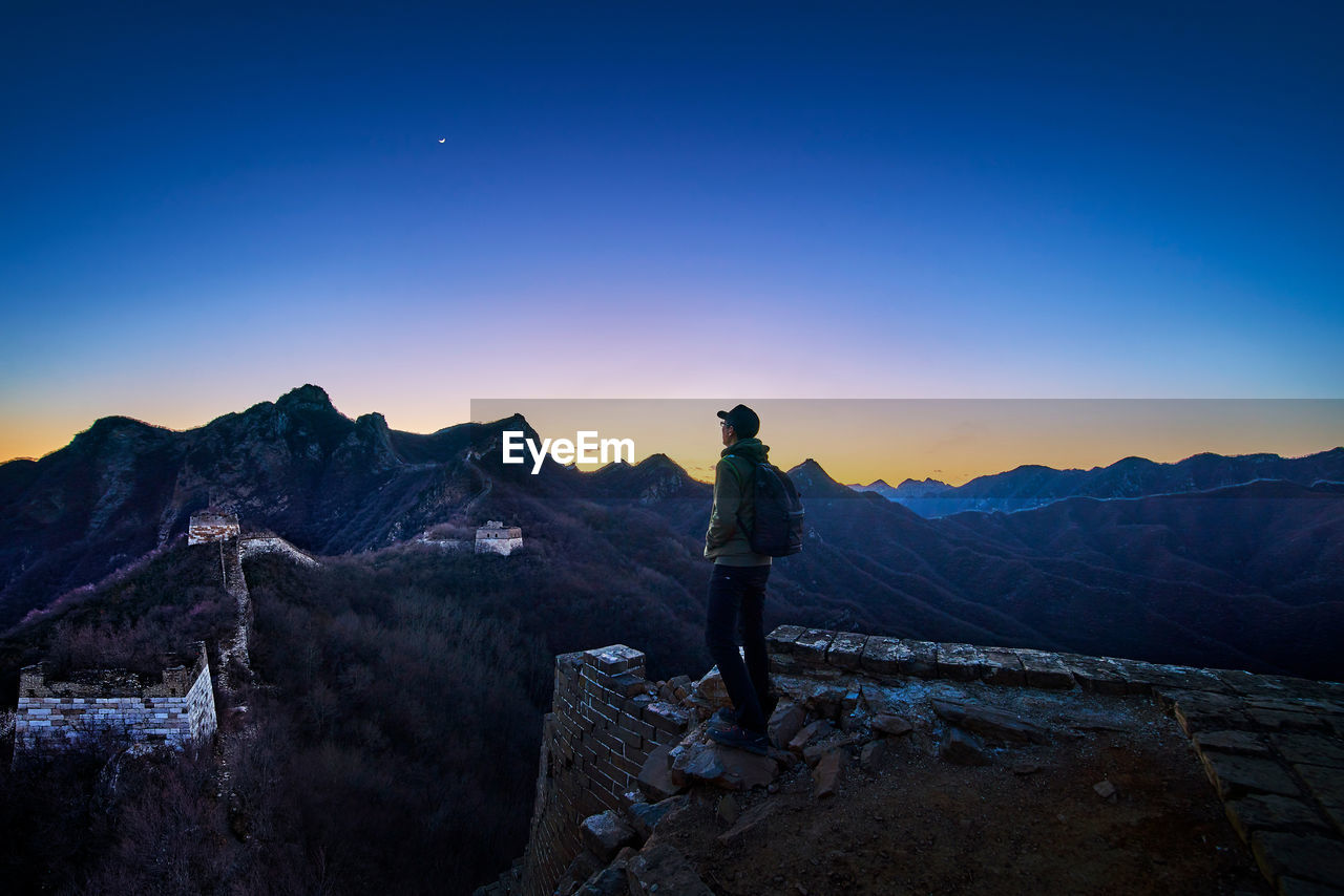 Side view of man standing on great wall of china during sunset