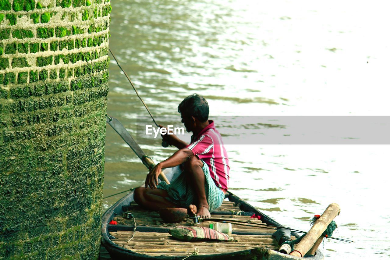 REAR VIEW OF BOY WORKING ON BOAT