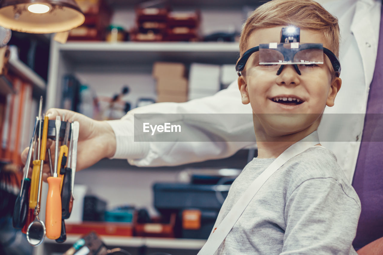 Happy kid with magnifying eyeglasses during physics experiment in engineering lab.