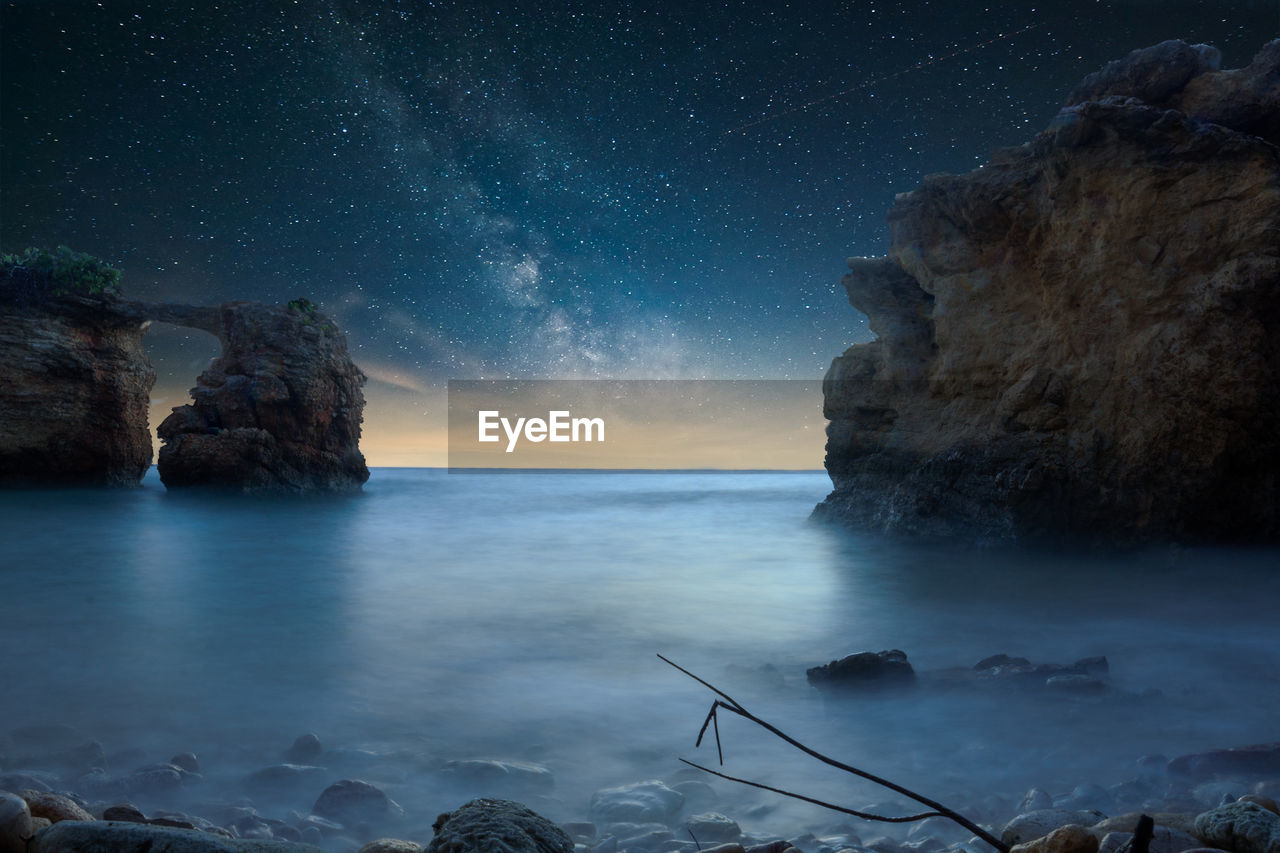 Rock formation in sea against sky at night