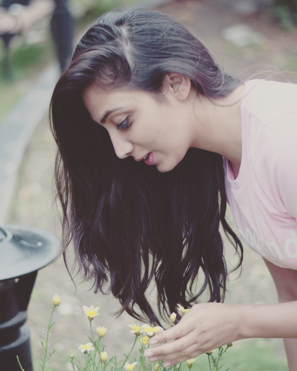 Beautiful woman looking at flowers in park