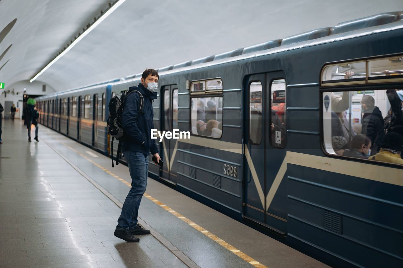 Man wearing mask standing on railroad station platform