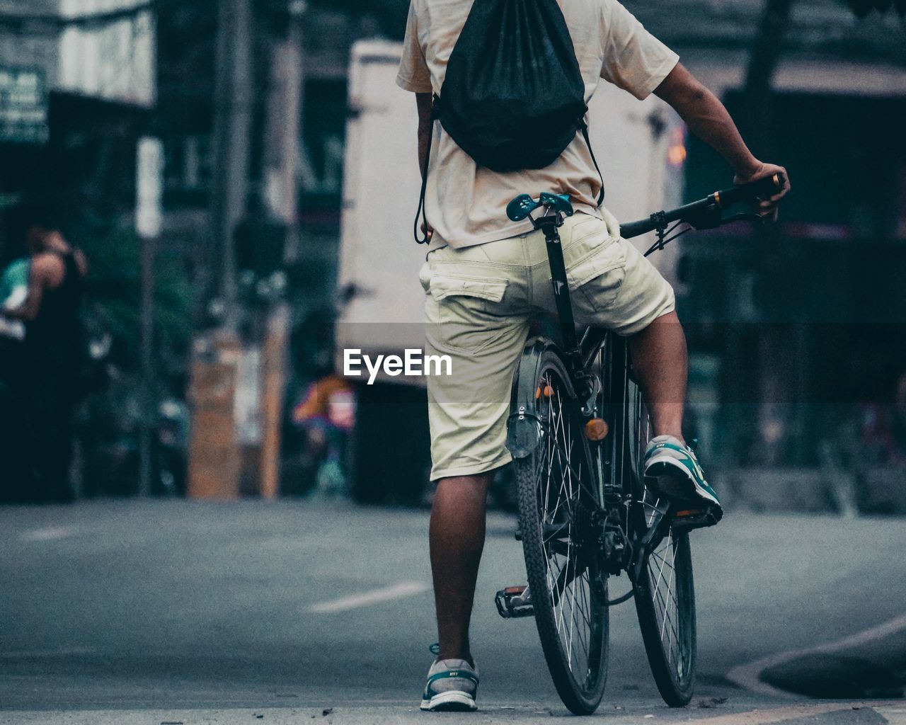 FULL LENGTH REAR VIEW OF MAN RIDING BICYCLE ON STREET