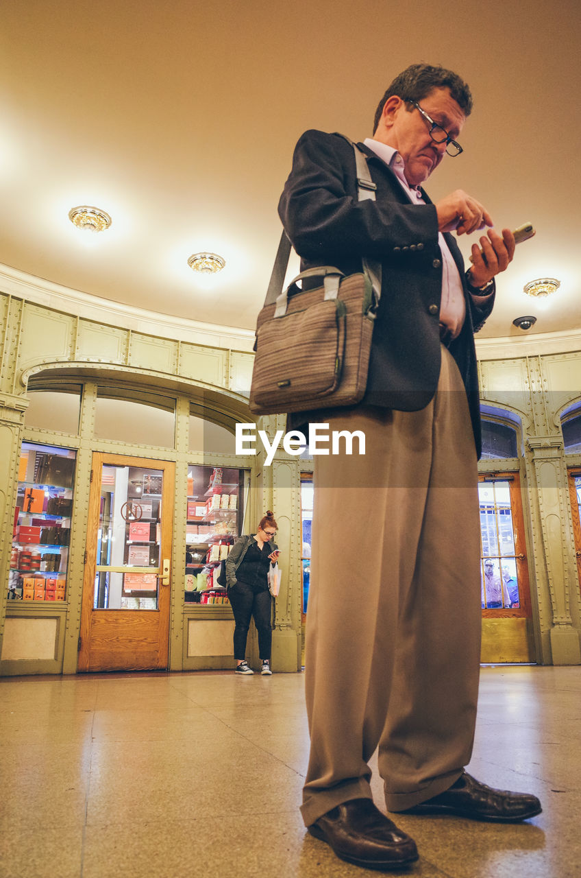 MAN LOOKING AT CAMERA WHILE STANDING IN ILLUMINATED UNDERGROUND