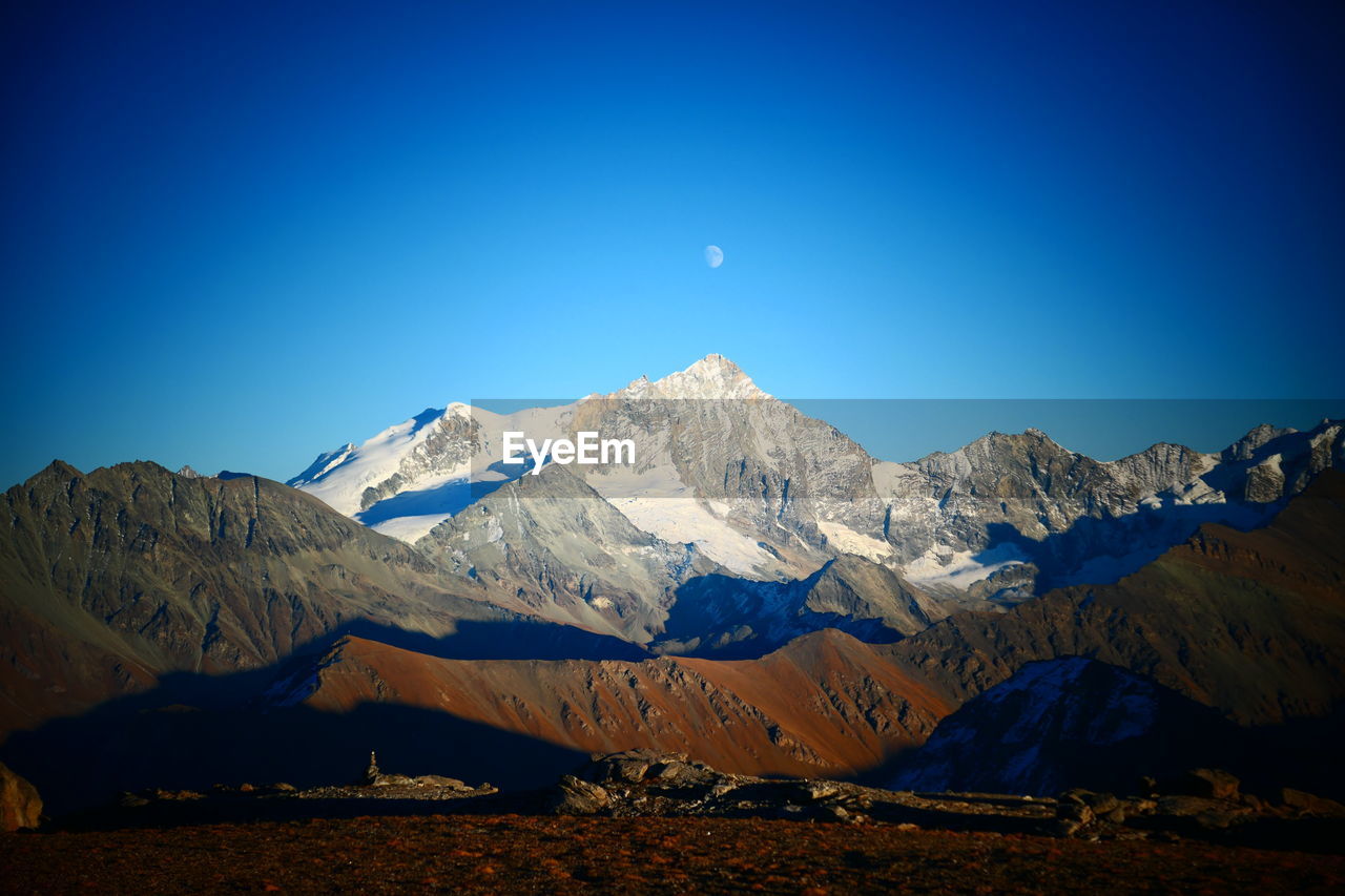 Scenic view of snowcapped mountains against blue sky