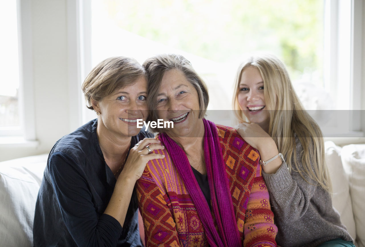 Portrait of happy three generation females in living room