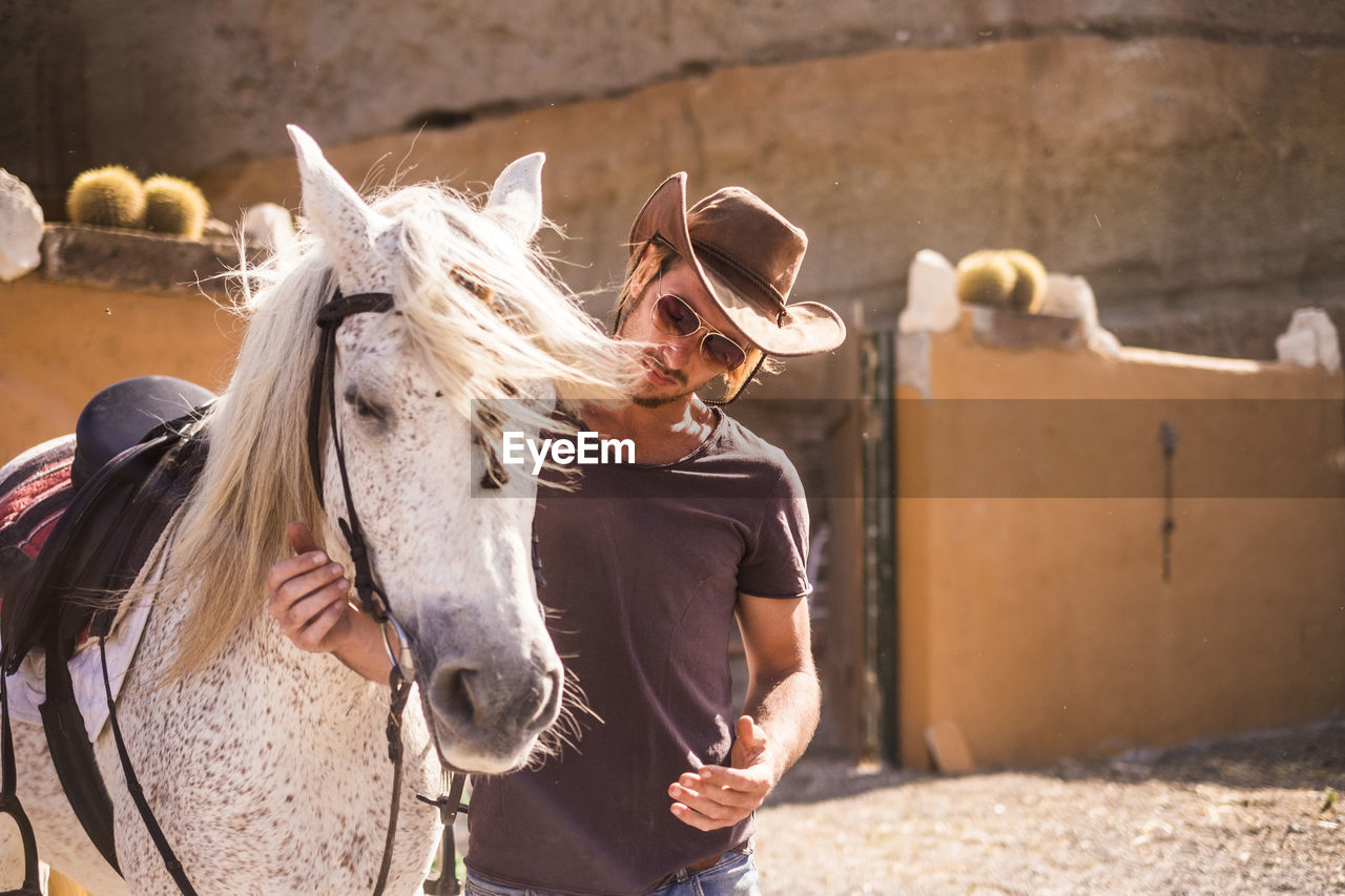 Man with horse standing at farm