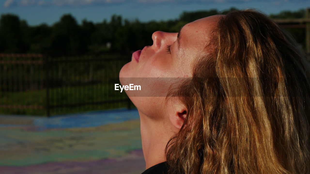 Side view of mid adult woman with eyes closed standing outdoors