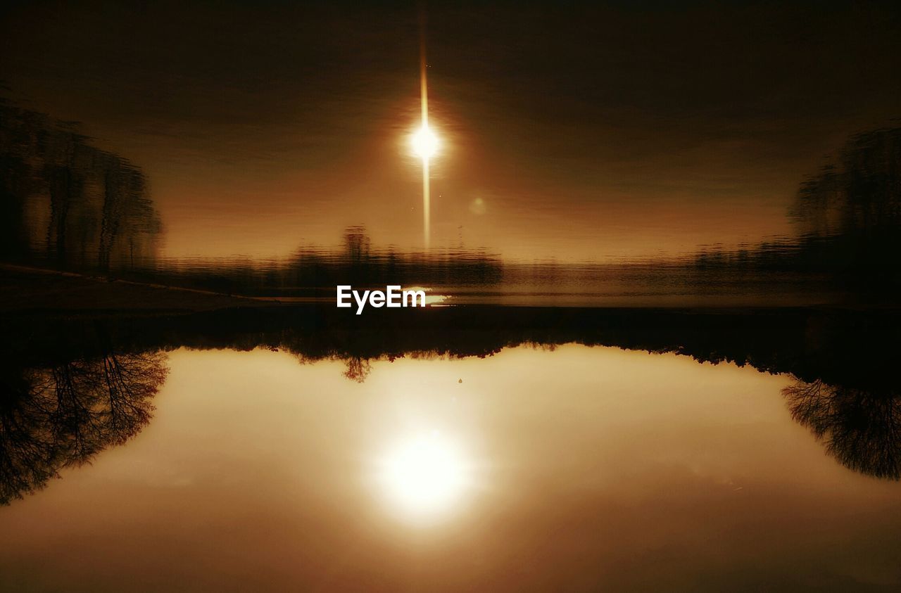 Scenic view of river by silhouette trees during sunset