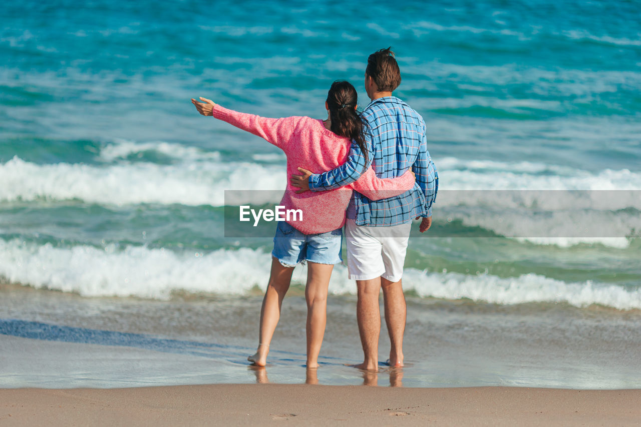 rear view of young man standing at beach