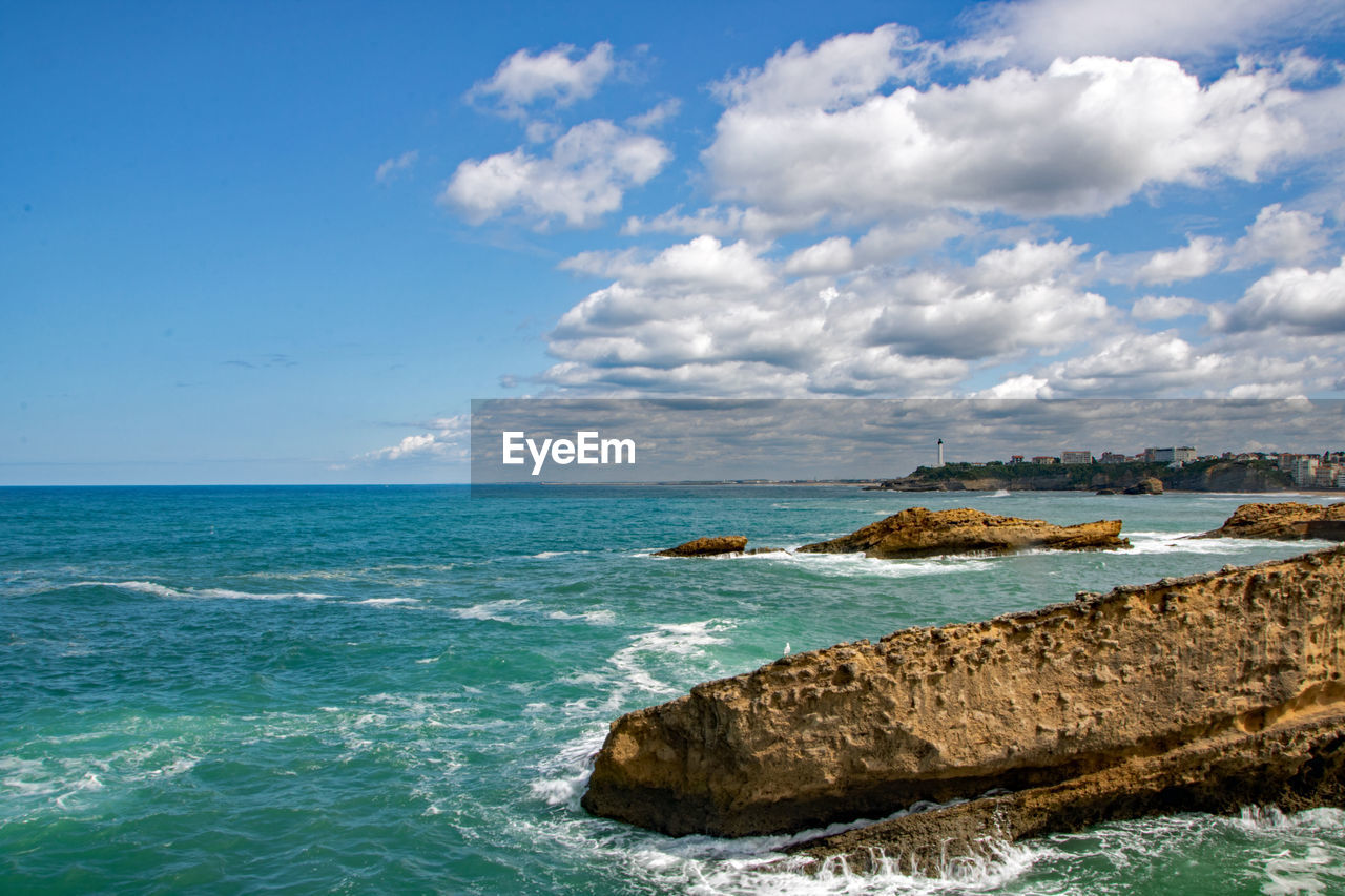 ROCKS BY SEA AGAINST SKY