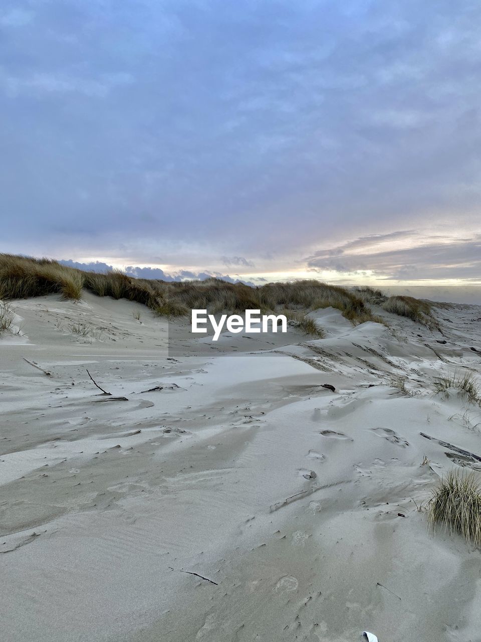 Scenic view of beach against sky during winter at sunset