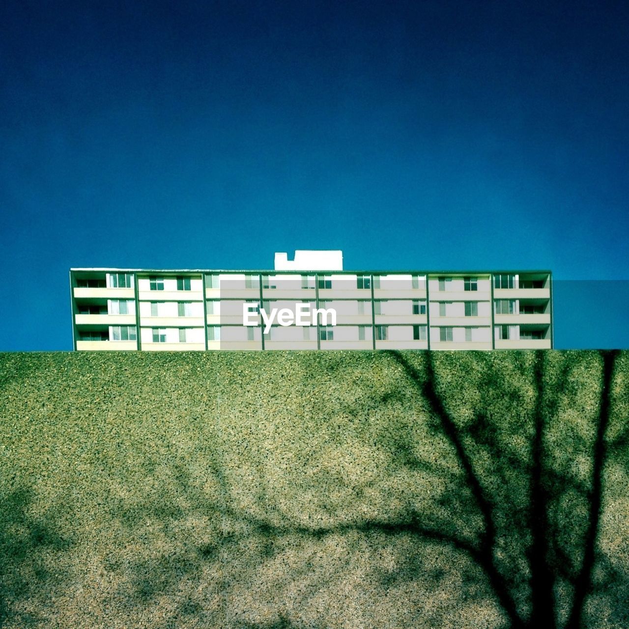 Shadow of wall in front of residential apartment building against clear blue sky