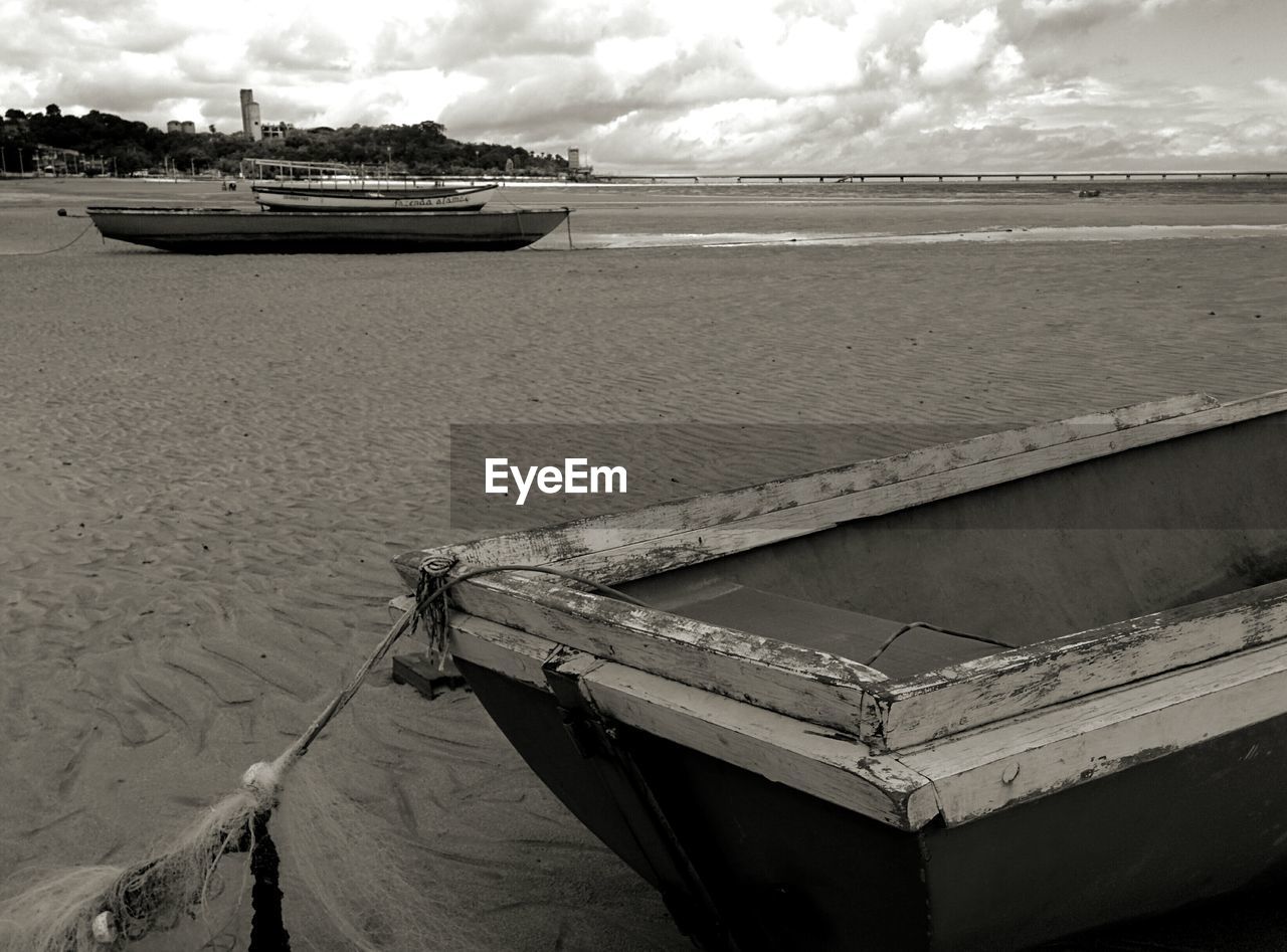 BOATS MOORED ON BEACH AGAINST SKY