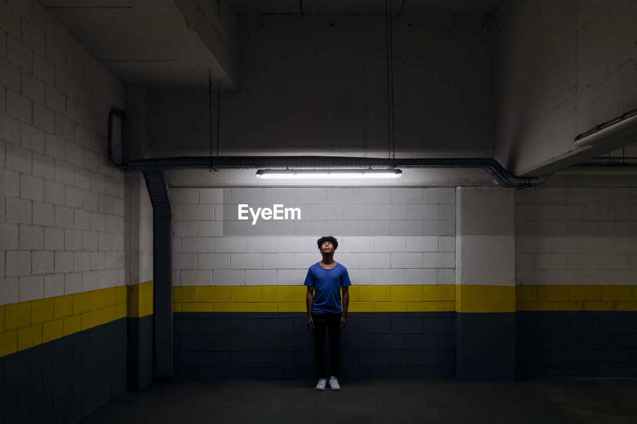 Young man looking at led light standing in subway