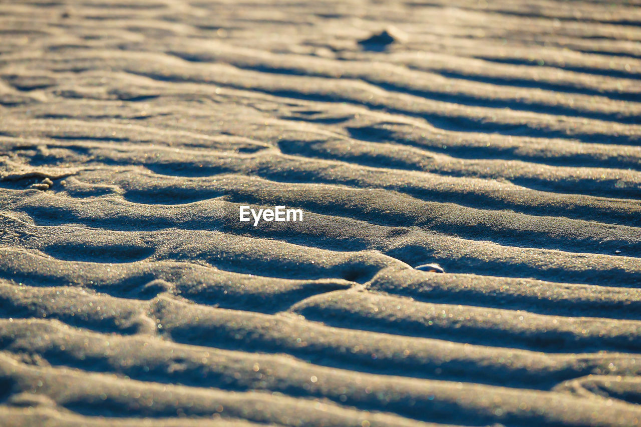 sand, pattern, land, backgrounds, full frame, no people, nature, day, sunlight, textured, beach, tranquility, beauty in nature, blue, outdoors, close-up, wood, high angle view, selective focus, scenics - nature, wave pattern, landscape