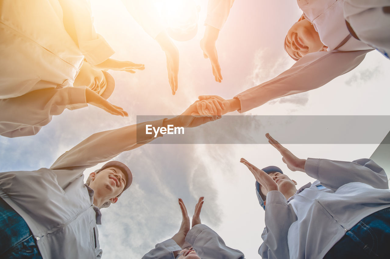 LOW ANGLE VIEW OF PEOPLE STANDING BY THE SKY