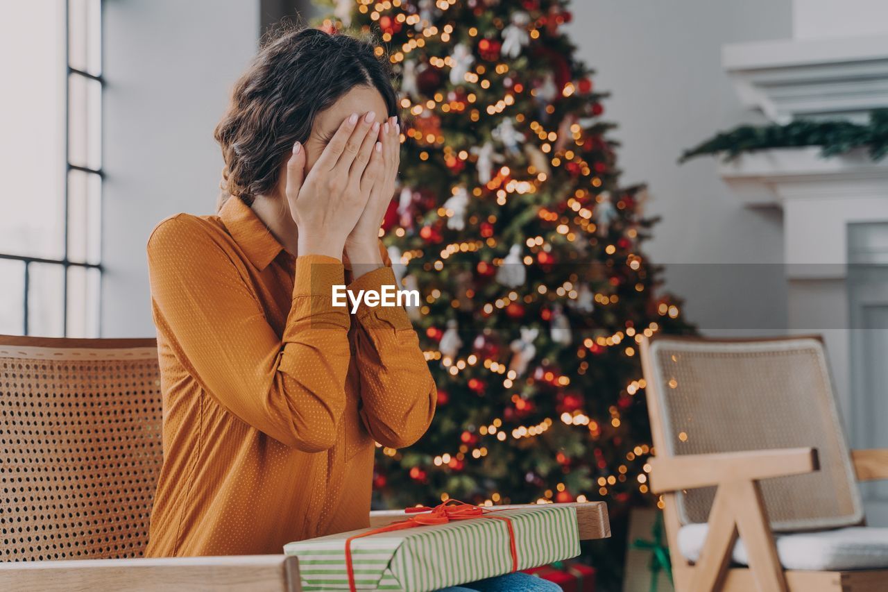 Midsection of woman with christmas tree at home