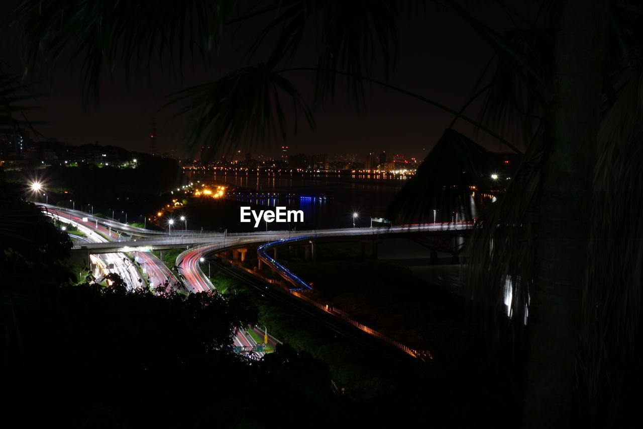 Illuminated bridge over river in city at night