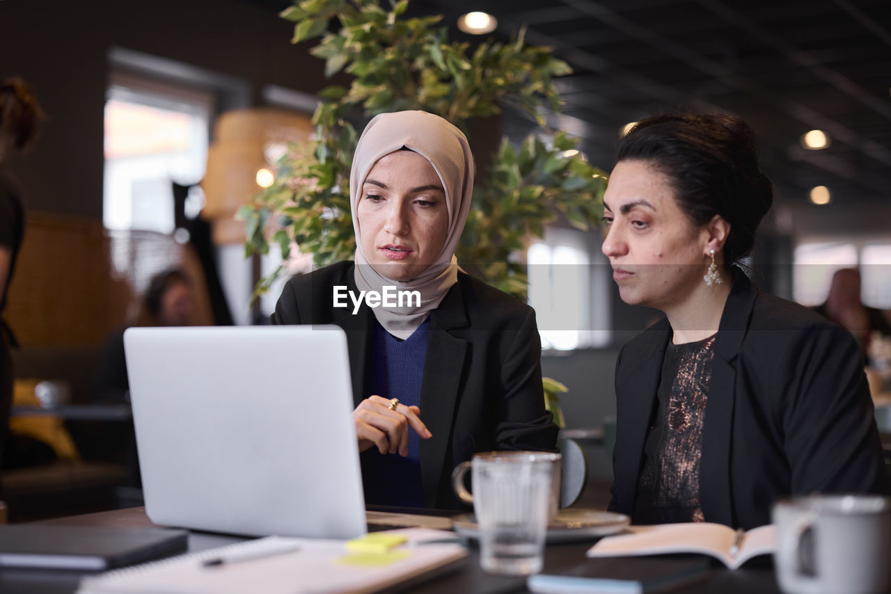 Businesswomen using laptop in cafe