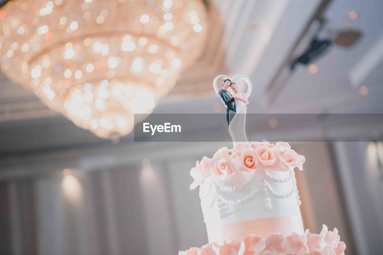 Close-up of illuminated candle with wedding cake