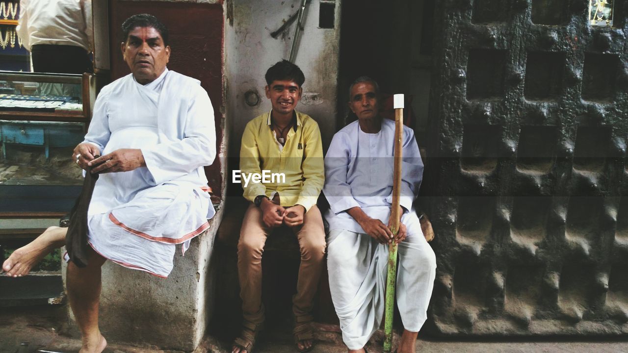 PORTRAIT OF YOUNG MEN STANDING AGAINST WALL